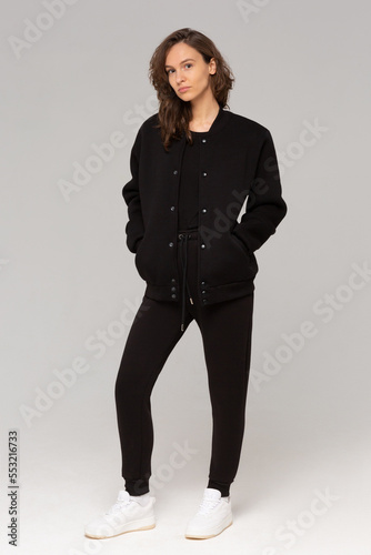 Smiling woman with thick curly hair in a black suit of hoodies and sweatpants. Mock-up.