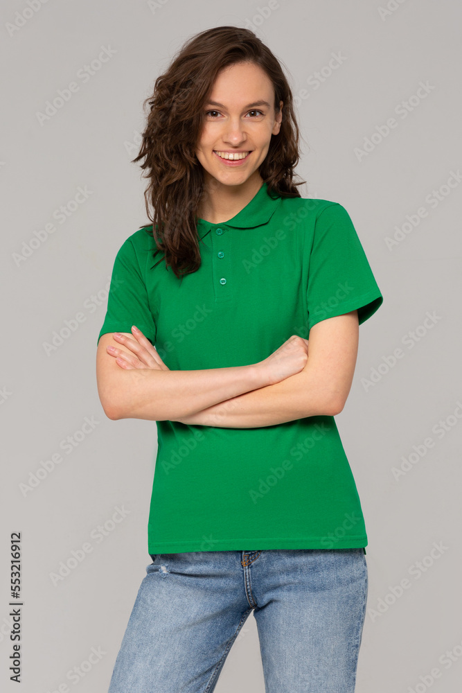 Green polo on a young woman in jeans, isolated, with copy space, mockup.