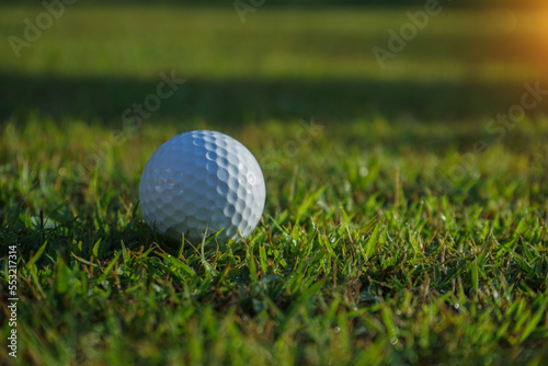 Golf ball on green in beautiful golf course at sunset background