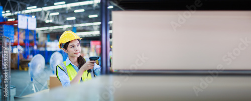 Young Asian women wearing yellow helmet stand behind the Containers box and Check in at the counter with using holding barcode scanner in the warehouse with copy space for text. Long banner photo