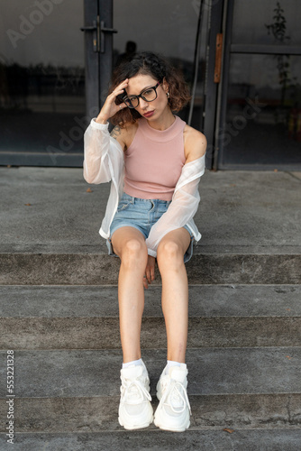 Beautiful curly woman sitting on steps  urban street portrait