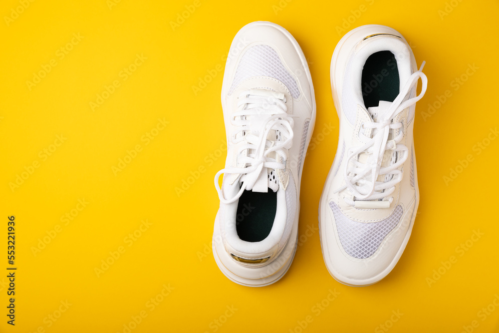A pair of white shoes on a yellow background. White stylish sneakers. STREET STYLE.Sports concept, unisex, sports shoes, lifestyle, concept, product photo, levitation concept, streetwear.