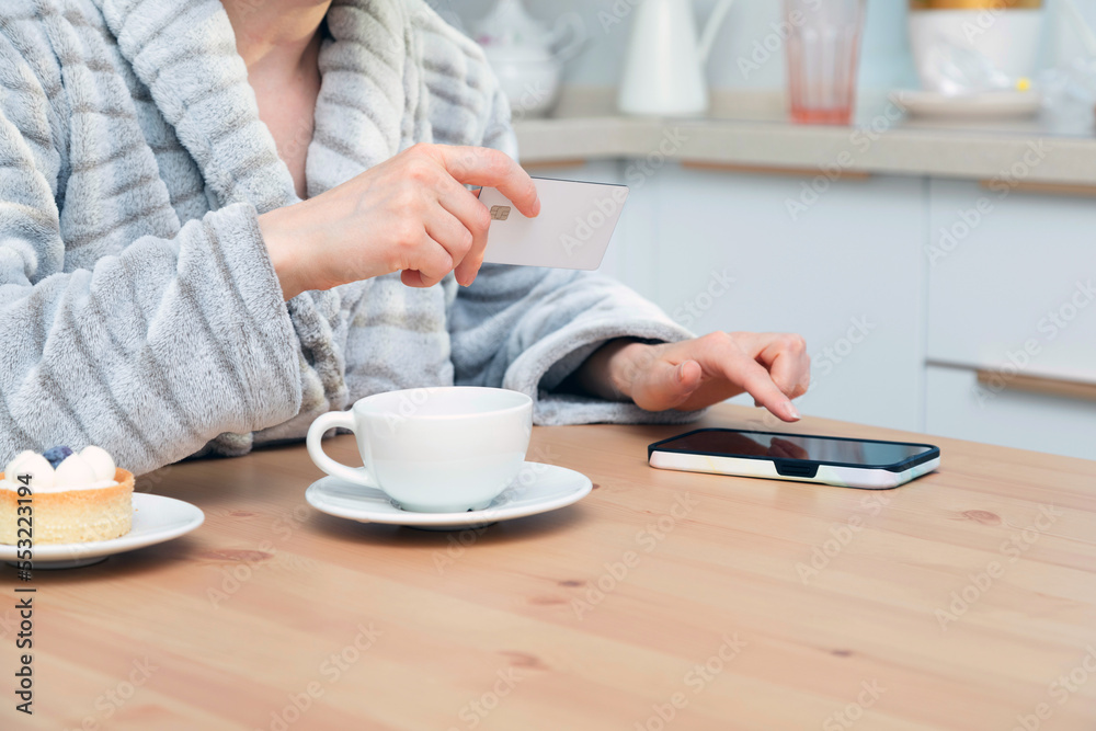 Woman using her debit card and smartphone to buy something online Woman using her debit card and smartphone to buy something online