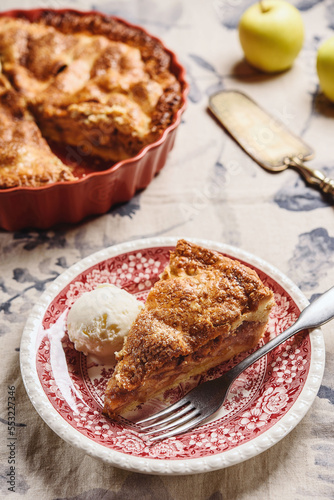 Classic American apple pie served with ice cream on linen tablecloth. Homemade american autumn dessert: sliced apple pie (tart) with cinnamon. Selective focus