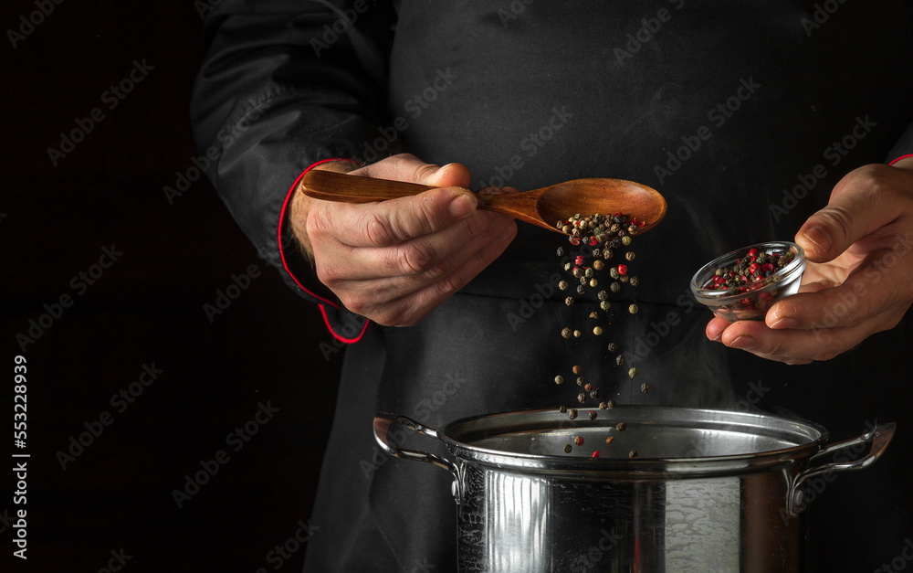 Chef adds aromatic peppers to a pot of boiling water while cooking ...