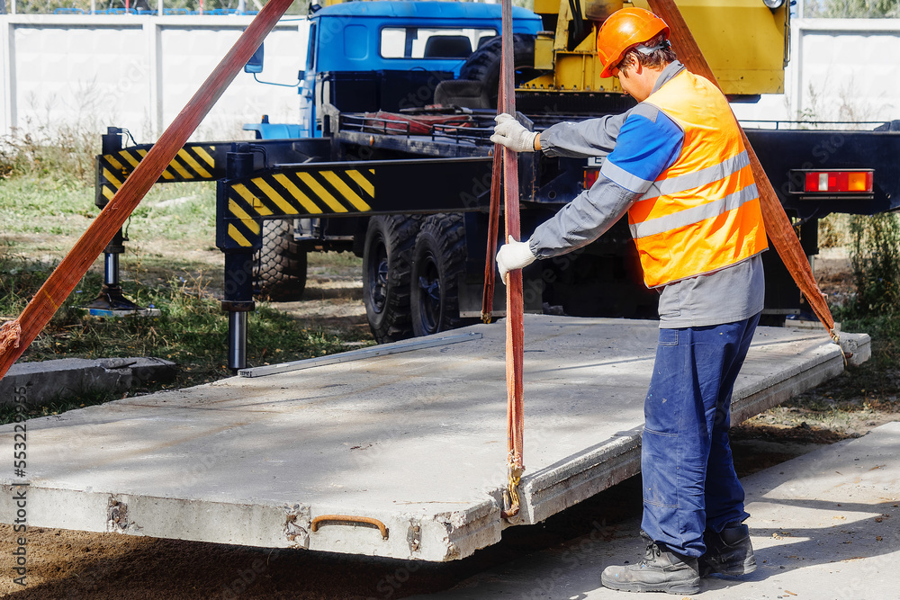 Fotografia do Stock Slinger lays concrete slab on construction site on