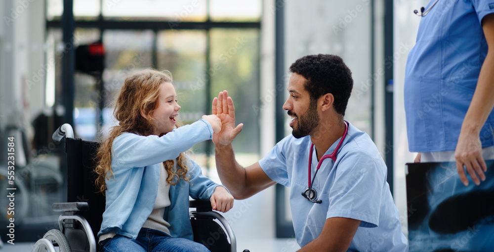Young multiracial doctor having fun with little girl on wheelchair. - obrazy, fototapety, plakaty 