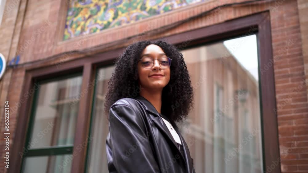 Portrait of young woman looking at camera while is touching her black jacket. She is in the city. Portrait of young woman looking at camera while is touching her black jacket. She is in the city.
