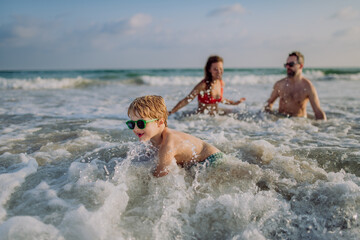 Happy family with little son enjoying time in sea in exotic country.