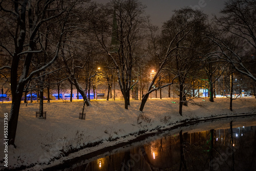 A river flowing through a park in the winter at night