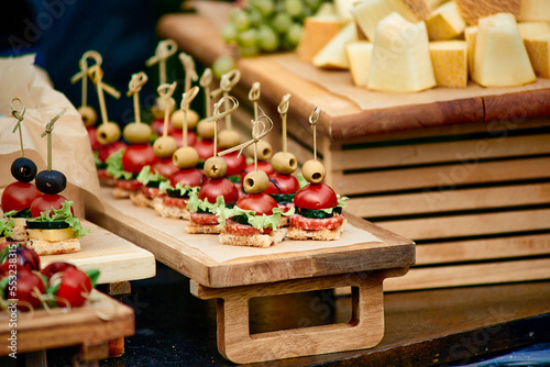 Catering. Buffet outside. Canape of tomatoes, cheese, meat, olives, lettuce, grapes, bread, melon.