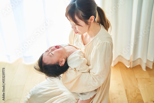 泣く幼児と抱っこするお母さん photo