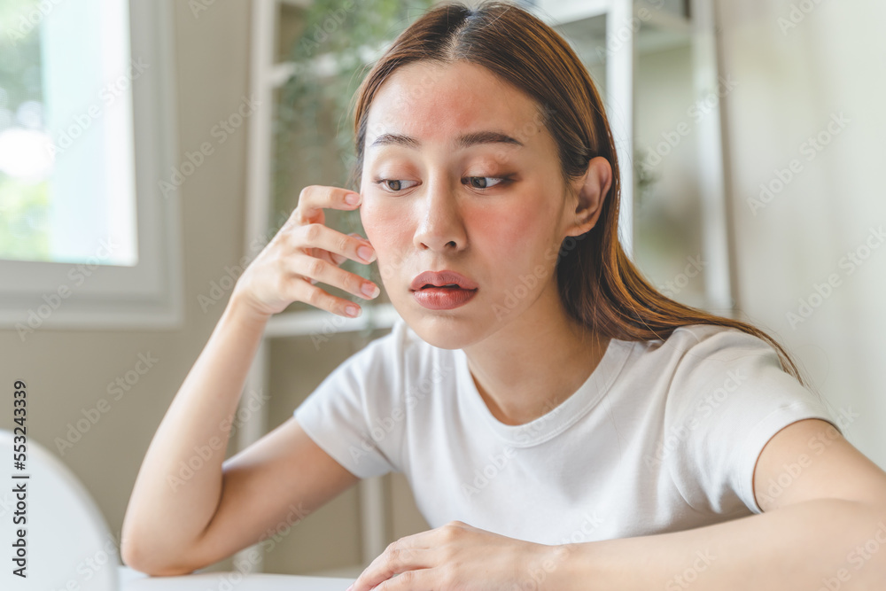 Sensitive skin with cosmetology, Asian young woman looking at red spot on her face from cosmetic allergy in the mirror. Sensitive skin with cosmetology, Asian young woman looking at red spot on her face from cosmetic allergy in the mirror.
