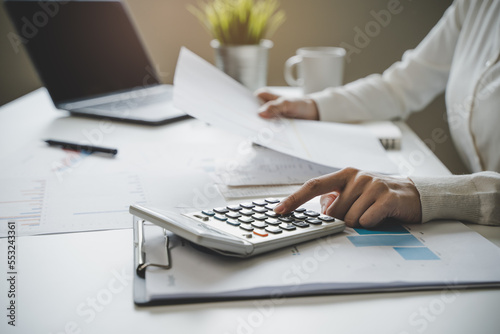 Fototapeta Naklejka Na Ścianę i Meble -  Women business people use calculators to calculate the company budget and income reports on the desk in the office.