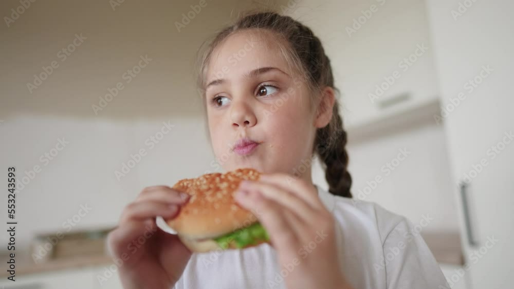 little kid girl eating a hamburger. unhealthy fast food meal proper