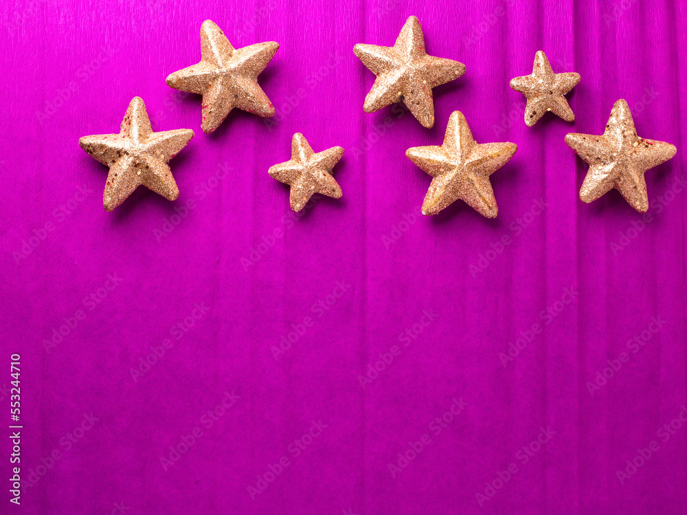 Border with big and small golden decorative stars on bright pink paper textured background. Top view. Christmas, New Year holidays concept. Place for text. Border with big and small golden decorative stars on bright pink paper textured background. Top view. Christmas, New Year holidays concept. Place for text.