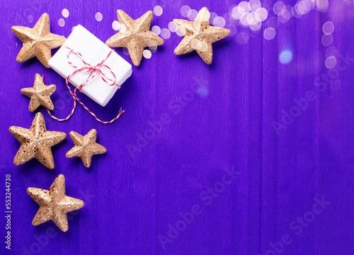 Border from wrapped boxes with presents and golden decorative stars on violet paper textured background. Place for text. Flat lay. Holiday layout.