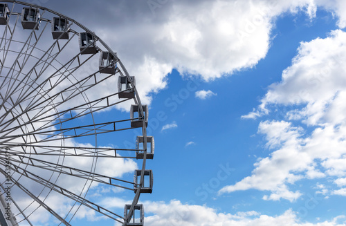 Ferris wheel and light blue sky with white clouds