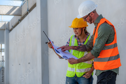 Engineering Consulting People on construction site holding blueprint in his hand. Building inspector. Construction site check drawing and business workflow of new building