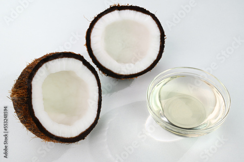 Coconut oil in a glass cup with split coconuts in the background.
