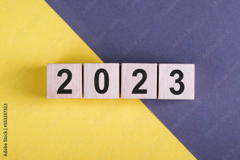 Woodblocks cubes square with number 2023 on yellow and gray background. Business goals next year. New year 2023 concept. Woodblocks cubes square with number 2023 on yellow and gray background. Business goals next year. New year 2023 concept.