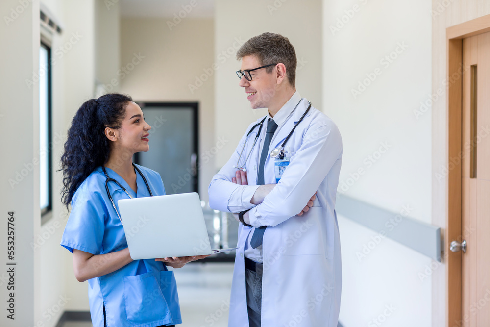 Clinicians in uniform standing and looking of computer monitor, discussing medical document and consulting. Doctor and nurse working on laptop in medical office. Professional medical work with Laptop Clinicians in uniform standing and looking of computer monitor, discussing medical document and consulting. Doctor and nurse working on laptop in medical office. Professional medical work with Laptop