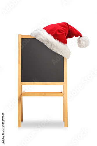 School blackboard with a wooden frame on a stand and santa claus hat on top