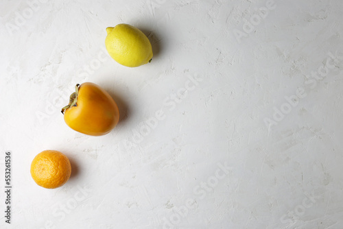 On a white background are lemon, tangerine, persimmon. Healthy food, copy space.