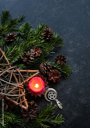 Candle  pentagram amulet  star  cones  fir branches on dark abstract background. Witchcraft Esoteric Ritual. symbol of Christmas  Yule  Winter Solstice wiccan holiday