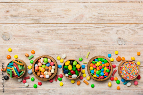different colored round candy in bowl and jars. Top view of large variety sweets and candies with copy space