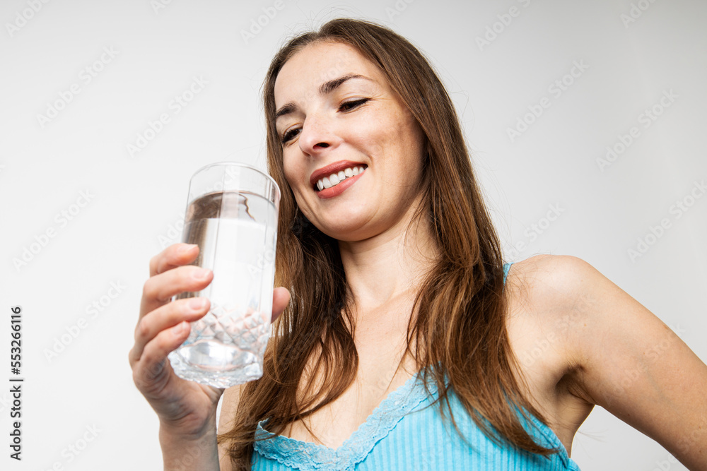 Smiling young woman holding a glass of water on a white background. Top view, flat lay Smiling young woman holding a glass of water on a white background. Top view, flat lay