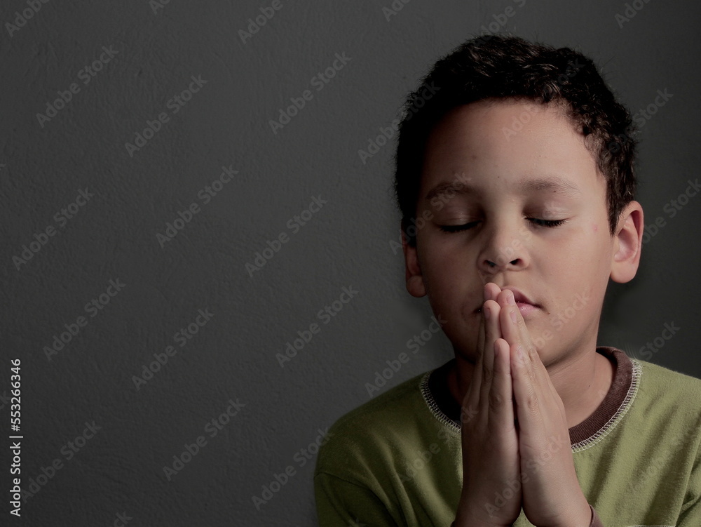 little boy praying to God with hands together with black background stock photo little boy praying to God with hands together with black background stock photo