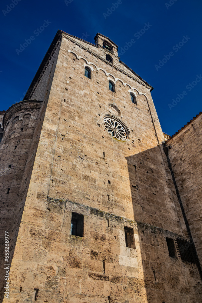 Side facade of the Cathedral Basilica of Santa Maria Annunziata, with the rose window and the apse, in Piazza Innocenzo III. Stone buildings from the Middle Ages. Anagni, Frosinone, Italy.