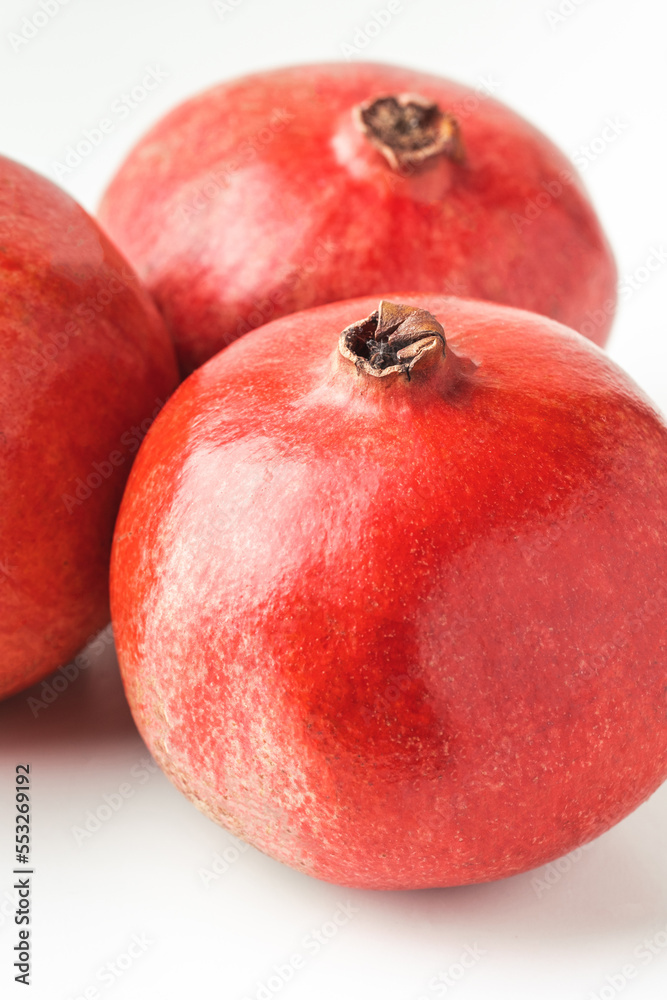 Fresh whole pomegranate fruits isolated on white background. Ripe pomegranates with glossy red peel Fresh whole pomegranate fruits isolated on white background. Ripe pomegranates with glossy red peel
