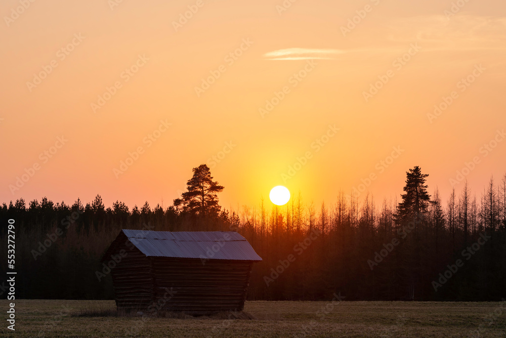 Sun setting over an old barn in a field. Österbotten/Pohjanmaa, Finland.