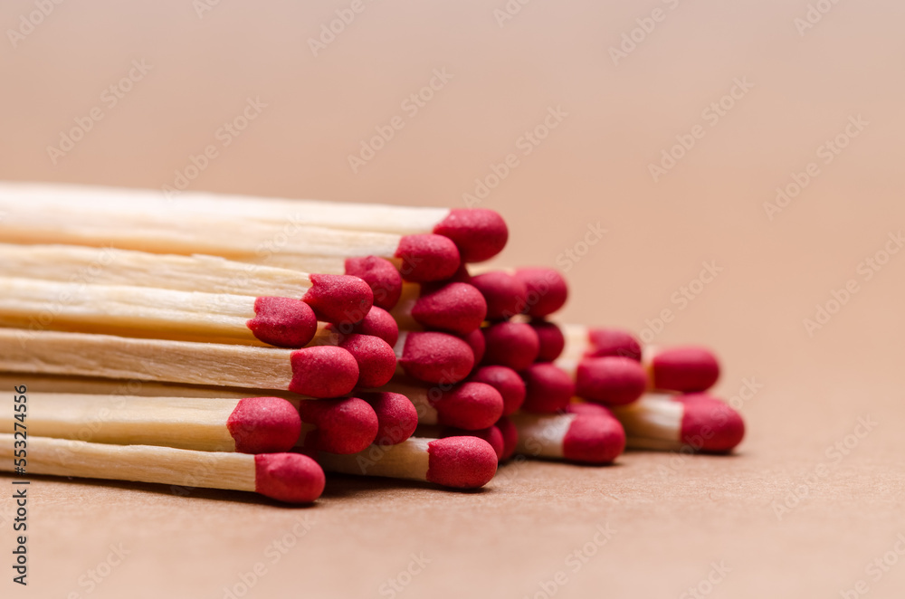 Close-up macro of a pile of new unlit wooden matchsticks on natural brown paper background Close-up macro of a pile of new unlit wooden matchsticks on natural brown paper background