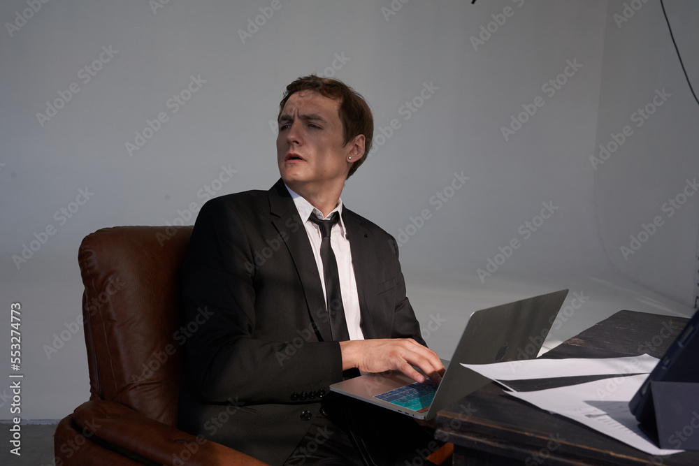 A young businessman is working on a laptop in the office. Business portrait of a businessman sitting in an office and working with a laptop computer. Space for copying. High quality photo
