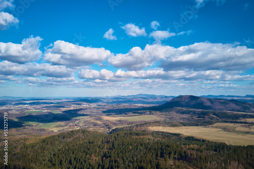 Fototapeta Naklejka Na Ścianę i Meble -  Clouds in blue sky with shadows on ground. A birds eye view of beautiful mountains covered with evergreen forest on sunny autumn day. Natural landscape with mountain ranges and valleys