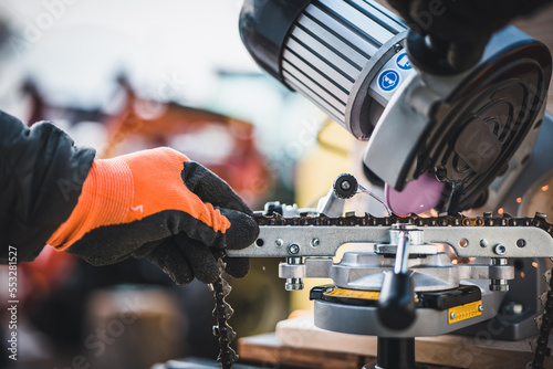 Sharpening motor chain or chainsaw chain with the use of a motorized grinder. Professional repairman sharpening a chain. Sharpening a chainsaw. photo