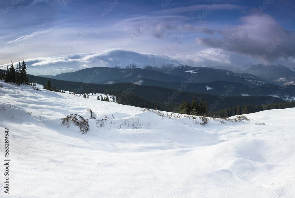 Panoramic landscape of the snow-capped mountain peaks on a sunny winter day. Carpathian mountains range. Europe.
