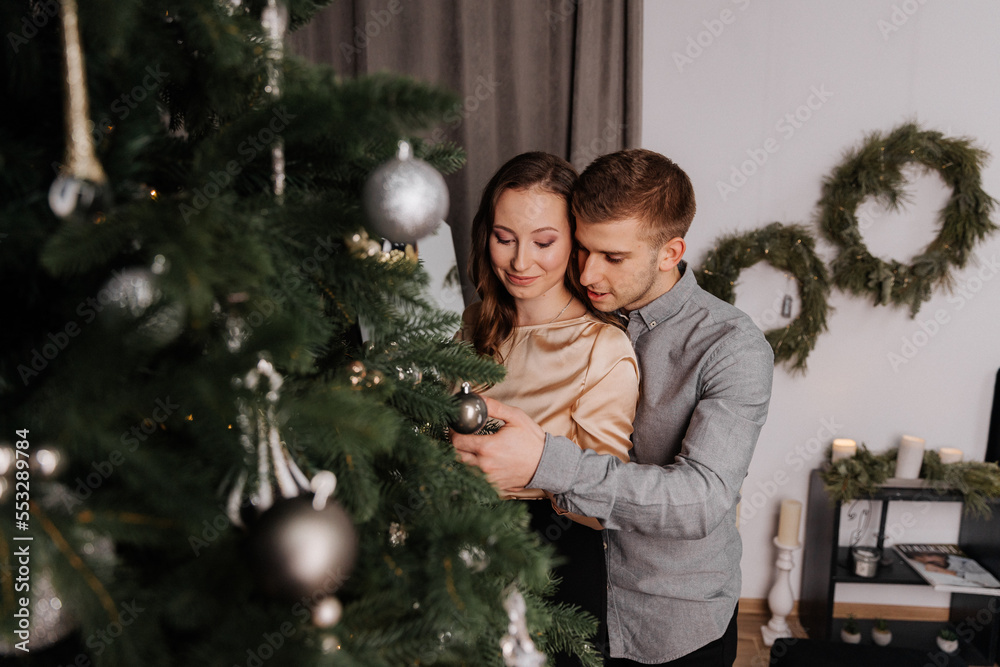 Young couple in love decorating the Christmas tree together Young couple in love decorating the Christmas tree together