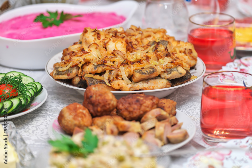 Festive table with food for New Year or Christmas. Pickled cucumbers and mushrooms, fried fish with onions, Shuba salad, chopped vegetables, fried cutlets, compote. Festive table with food for New Year or Christmas. Pickled cucumbers and mushrooms, fried fish with onions, Shuba salad, chopped vegetables, fried cutlets, compote.