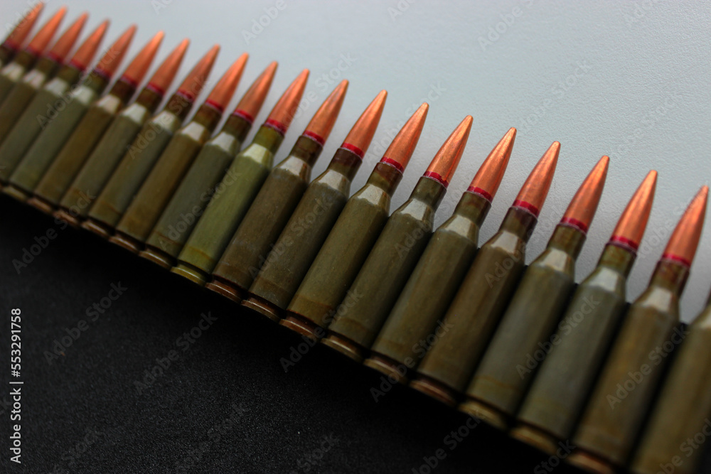 An even row of bullets lie on a background separated into a black and white field angle view
An even row of bullets lie on a background separated into a black and white field angle view