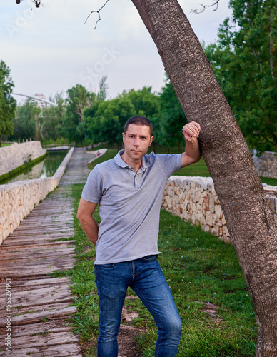 A model leaning on a tree in a park