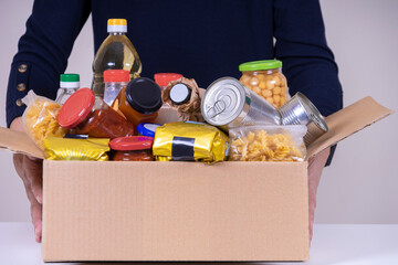Woman volunteer hands holding food donation box with food grocery products. Donations for charity, food bank
