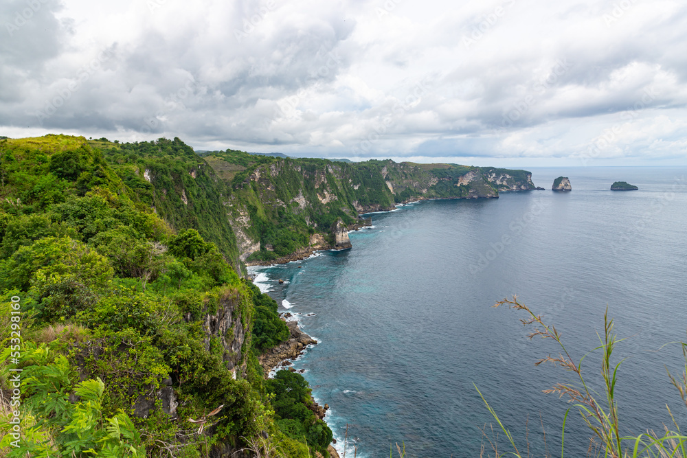 Beautiful coastline view from Saren Cliff Point. Clear water and rocks with cloudy sky. Nusa Penida, Indonesia.