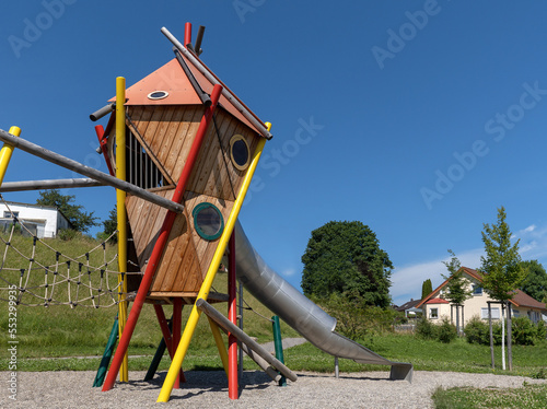 Moderner bunter Spielturm mit Tunnelrutsche auf einem öffentlichen Spielplatz in einer ländlichen Siedlung photo