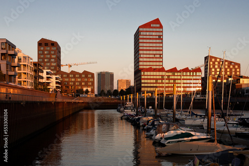 sunset reflecting on newly built modern office and residential buildings on the head of a harbour during golden hour