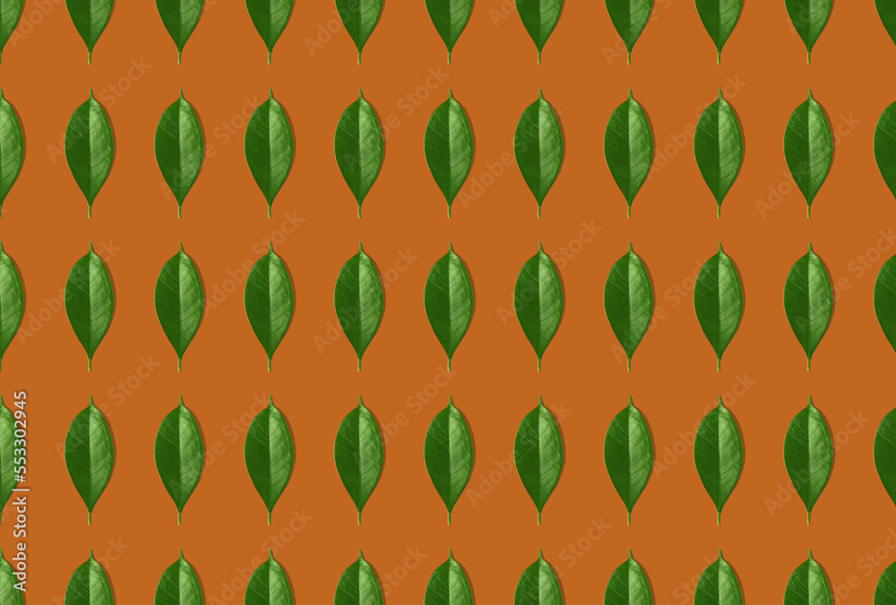Fototapeta premium Creative seamless pattern of green leaves on orange background. Creative design in flat lay style. Top view. Mock-up.