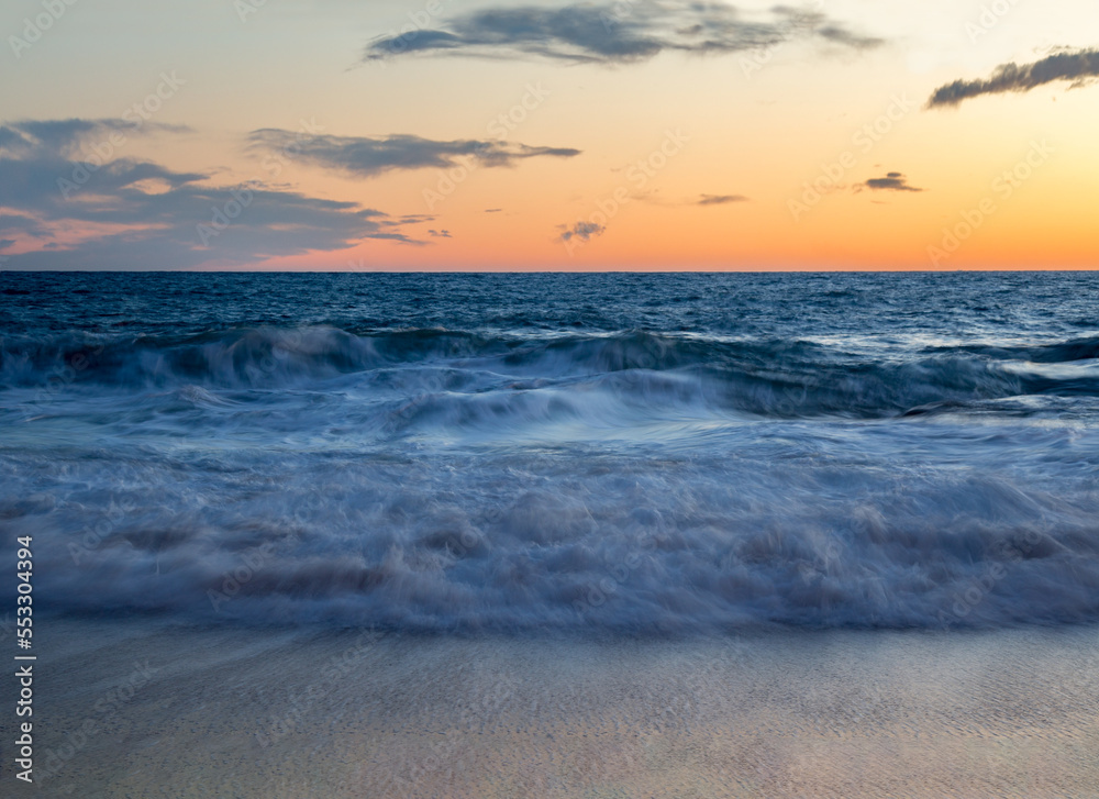 Waves in the Mediterranean sea with orange sunset.